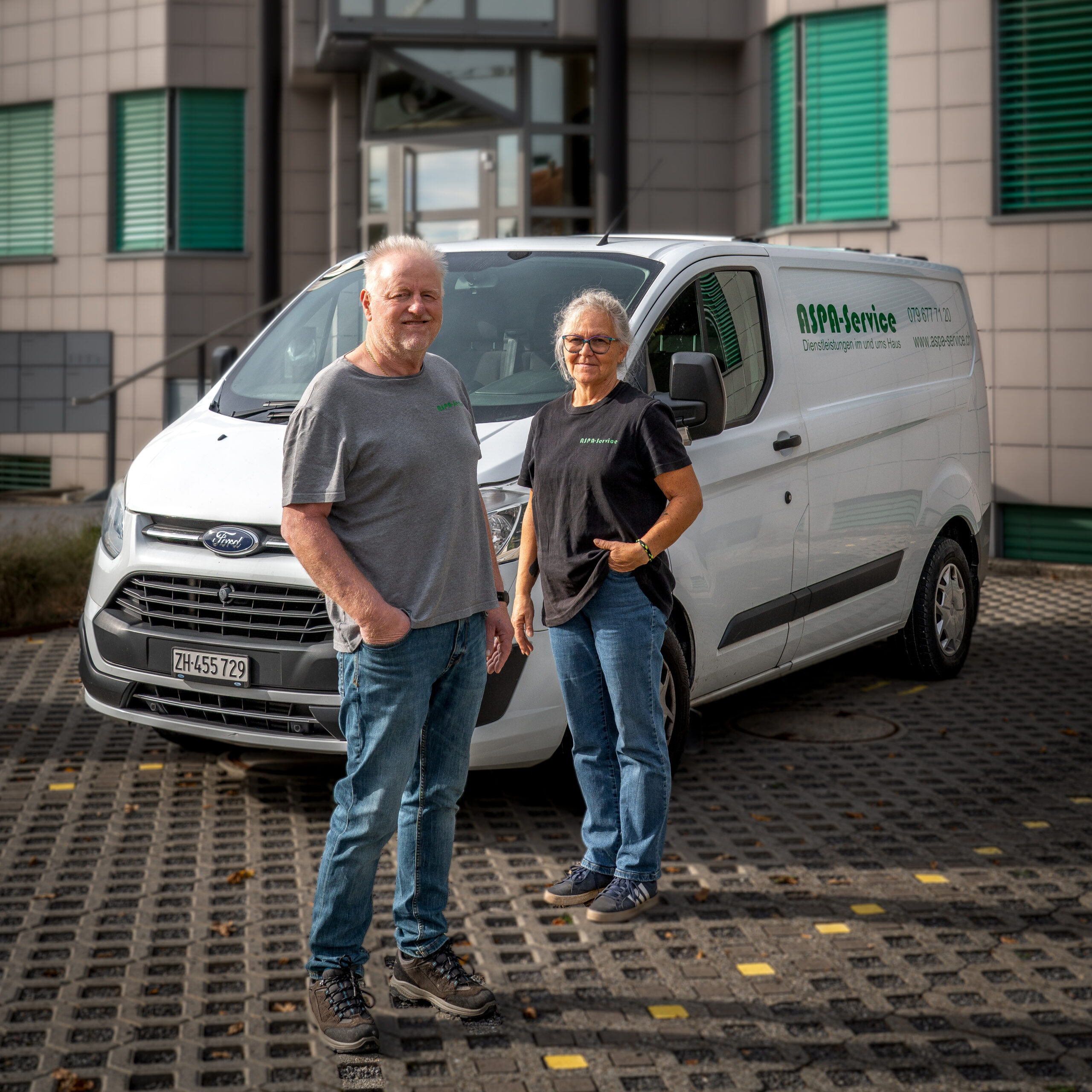 Inhaber stehen vor dem Firmenauto vor einer Liegenschaft.